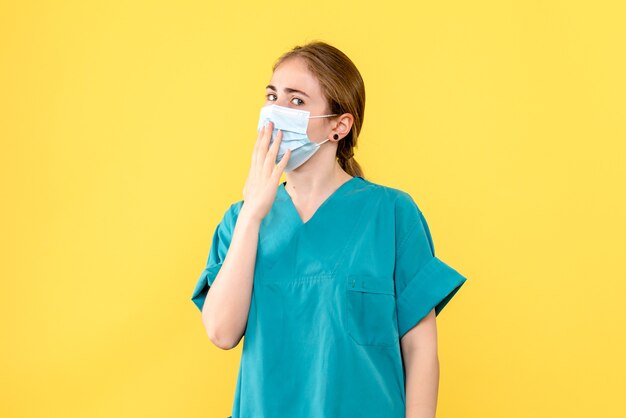 Vorderansicht Ärztin in Maske auf gelbem Hintergrund Gesundheitspandemie-Covid-Virus