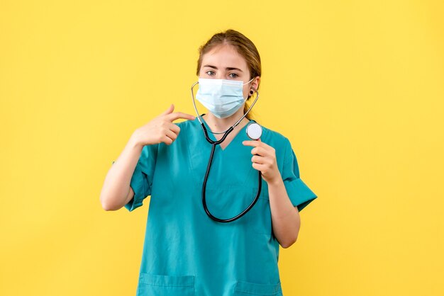 Vorderansicht Ärztin in Maske auf gelbem Hintergrund Gesundheitspandemie covid