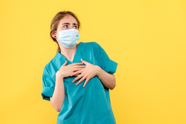 Vorderansicht Ärztin in Maske auf gelbem Hintergrund Krankenhausgesundheits-Covid-Pandemie