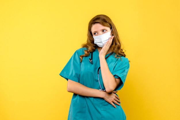 Vorderansicht Ärztin in Maske auf gelbem Raum