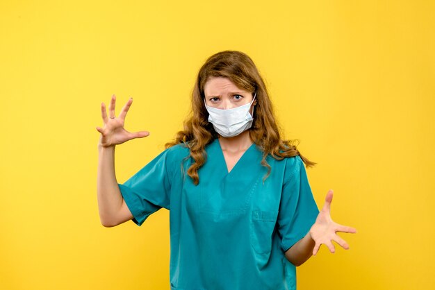 Vorderansicht Ärztin in Maske auf gelbem Raum