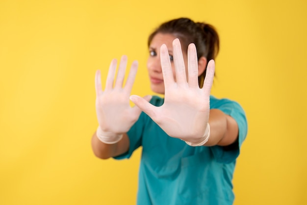 Vorderansicht Ärztin in medizinischen Handschuhen auf gelbem Hintergrund