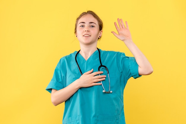 Vorderansicht Ärztin in schwörender Pose auf gelbem Hintergrundgefühlskrankenhausgesundheitsmediziner