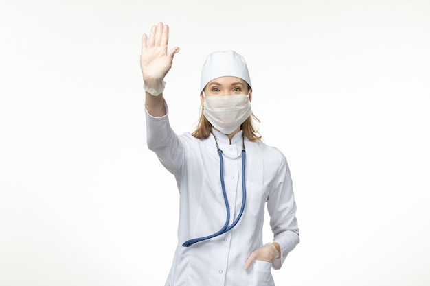 Vorderansicht Ärztin in weißem Anzug und Maske als Schutz vor Coronavirus an der weißen Wand Krankheit Covid-Krankheit