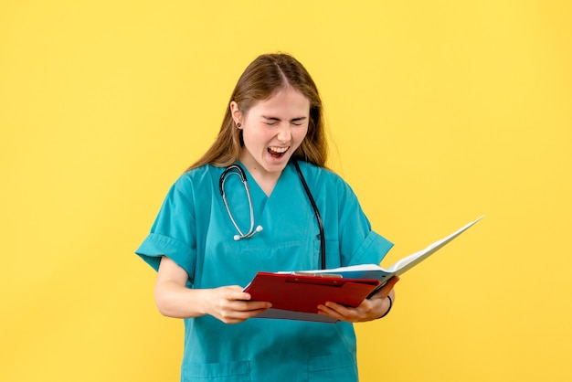 Vorderansicht Ärztin mit Analysen auf gelbem Hintergrund Krankenschwester Krankenhausgesundheit