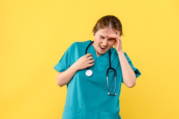 Vorderansicht Ärztin mit Kopfschmerzen auf gelbem Hintergrund Emotion Hospital Health Medic