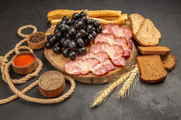 Vorderansicht-Schinkenscheiben mit Traubengewürzen und Brotscheiben auf dunklem Snack-Farbfoto-Fleischmahlzeit