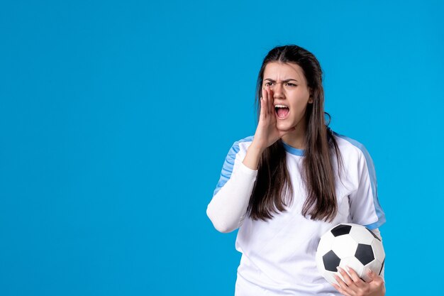 Vorderansicht schreiende junge Frau, die Fußball hält