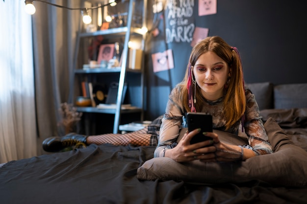 Kostenloses Foto vorderansicht-smiley-mädchen, das smartphone hält