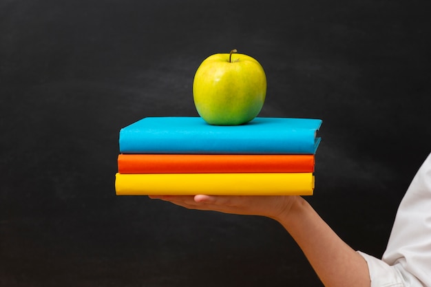 Kostenloses Foto vorderansicht stapel bücher mit apfel oben