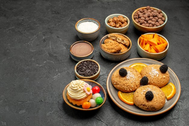 Vorderansicht süße Kekse mit Pommes und Orangenscheiben auf dunklem Hintergrund Fruti Keks Keks süßer Kuchen Kuchen
