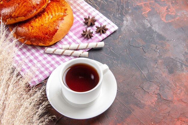 Vorderansicht süße Kuchen mit Tasse Tee auf dunklem Tischkuchen Kuchen Gebäck süß