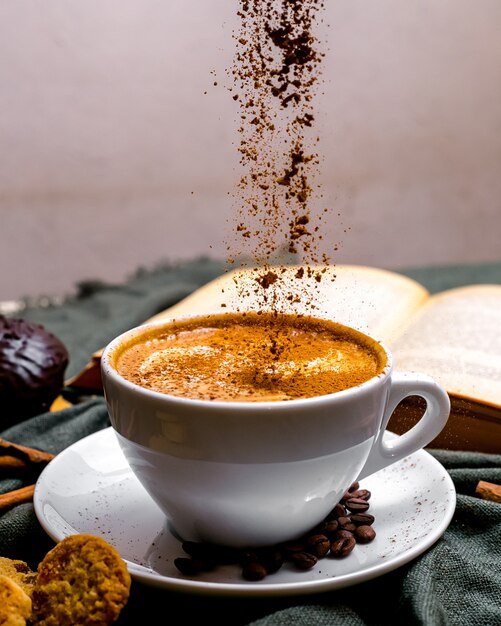 Vorderansicht Tasse Cappuccino mit Keksen und einem Buch auf dem Tisch