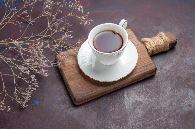 Vorderansicht Tasse Tee in Glastasse mit Teller auf dem dunklen Raum