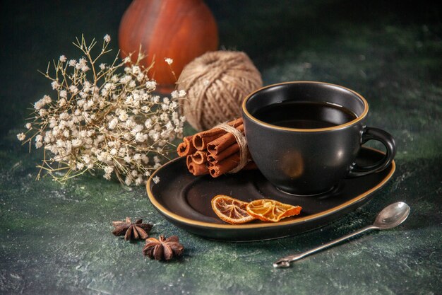 Vorderansicht Tasse Tee in schwarzer Tasse und Teller mit Zimt auf dunkler Oberfläche Zucker Zeremonie Glas Frühstück Dessert süßen Kuchen