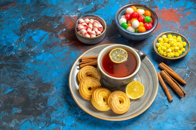 Vorderansicht Tasse Tee mit Keksen und Bonbons auf blauem Tisch Keks Süßigkeiten Tee