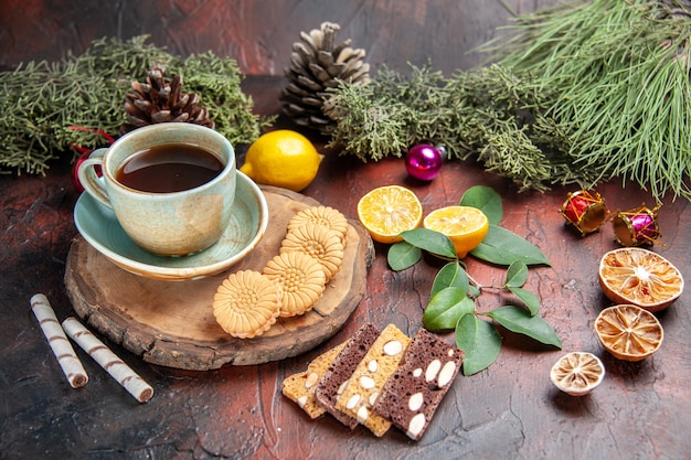 Vorderansicht Tasse Tee mit Keksen und Kuchen auf dunklem Hintergrund