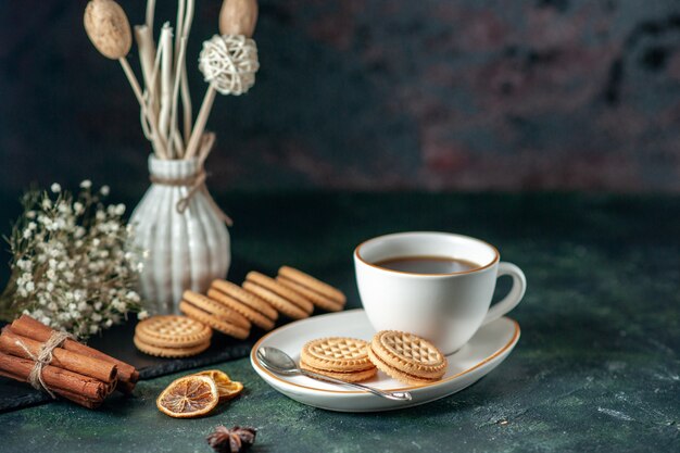 Vorderansicht Tasse Tee mit kleinen süßen Keksen in weißer Platte auf dunkler Oberfläche Brot trinken Farbzeremonie Frühstück Morgen Glas Foto