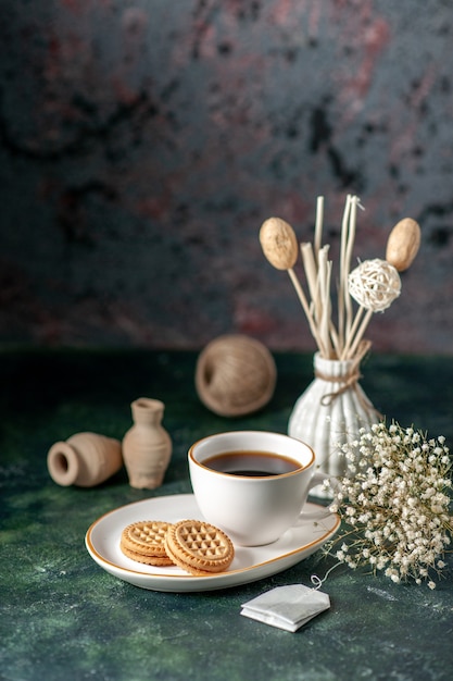 Vorderansicht Tasse Tee mit kleinen süßen Keksen in weißer Platte auf dunkler Oberfläche Farbzeremonie Frühstück Morgen Foto Brot Glas Zucker