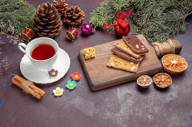 Vorderansicht Tasse Tee mit Kuchenscheiben auf dunklem Raum