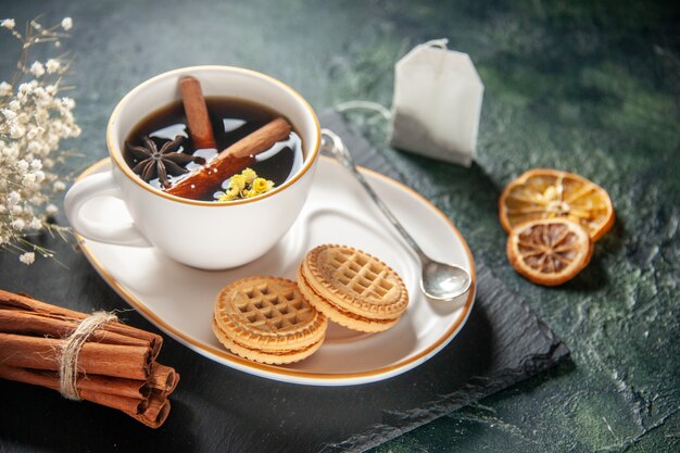 Vorderansicht Tasse Tee mit süßen Keksen auf dunkler Oberfläche Brot Getränk Zeremonie Glas süßes Frühstück Morgen Zuckerkuchen Farbfotos