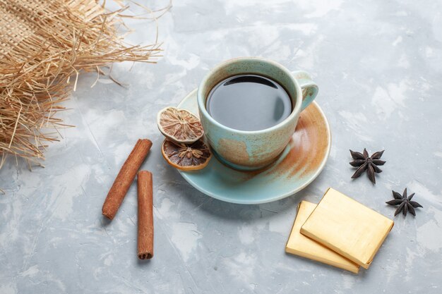 Vorderansicht Tasse Tee mit Süßigkeiten und Zimt auf dem weißen Schreibtisch Tee Süßigkeiten Farbe Frühstück