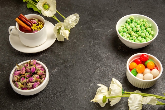 Vorderansicht Tasse Tee mit verschiedenen Bonbons auf Grauraum