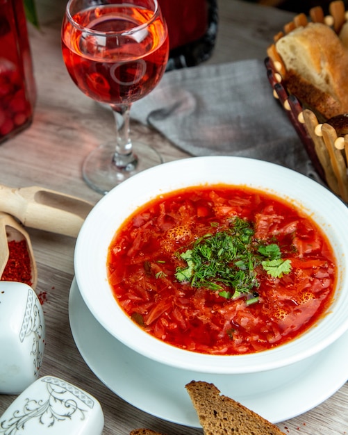 Vorderansicht traditioneller ukrainischer Borschtsch mit Scheiben Schwarzbrot und einem alkoholfreien Getränk