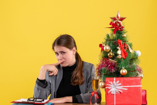 Vorderansicht trauriges süßes Mädchen, das am Schreibtisch sitzt Finger setzt