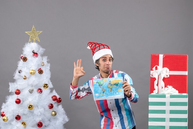 Vorderansicht überraschte Mann mit Spiralfeder Santa Hut, der okey Zeichen macht