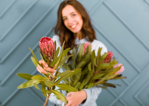 Kostenloses Foto vorderansicht unscharfe frau, die mit blumen aufwirft