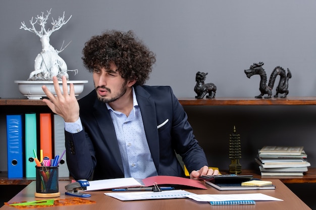 Kostenloses Foto vorderansicht unzufriedener geschäftsmann, der am schreibtisch im büro sitzt