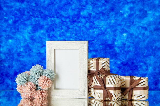 Vorderansicht valentinstag geschenke blumen weißer fotorahmen reflektiert auf spiegel auf blauem unscharfem hintergrund