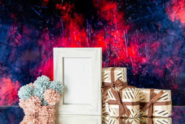 Vorderansicht valentinstag geschenke gebunden mit bandblumen weißer fotorahmen reflektiert auf spiegel auf dunkelrotem abstraktem hintergrund