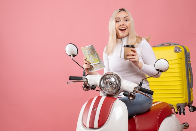 Vorderansicht verblüffte junge Dame auf Moped mit gelbem Koffer