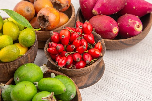 Vorderansicht verschiedene frische früchte in platten auf weißem hintergrund farbe tropisches gesundes leben exotischer beerenbaum reif