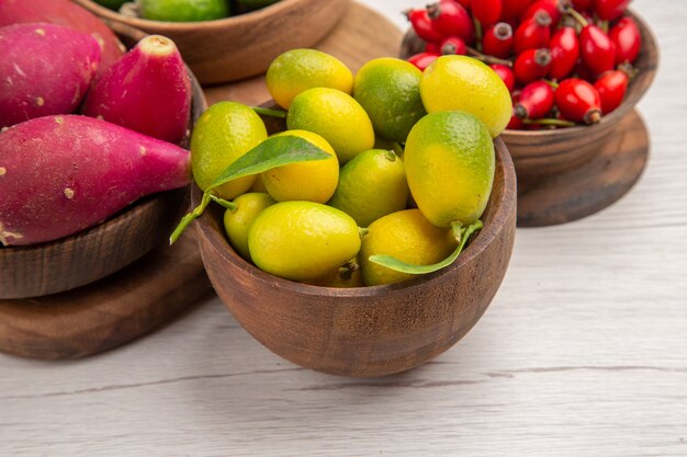 Vorderansicht verschiedene Früchte Feijoas Beeren und andere Früchte in Platten auf weißem Hintergrund reifes Essen exotische tropische Fotofarbe