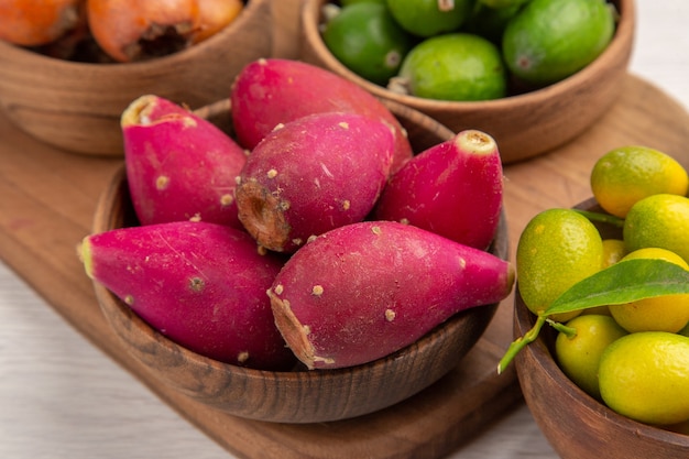 Vorderansicht verschiedene Früchte Feijoas Beeren und andere Früchte in Platten auf weißem Hintergrund reifes Essen exotische tropische Fotofarbe