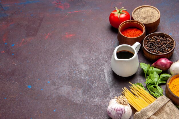 Vorderansicht verschiedene Gewürze mit roher Pasta auf dunklem Raum