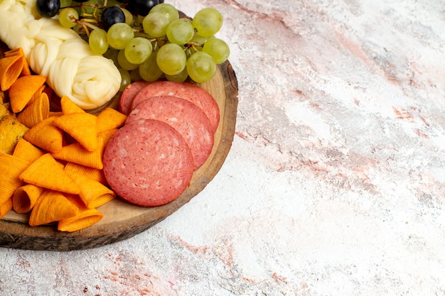 Kostenloses Foto vorderansicht verschiedene snacks cips würstchen käse und frische trauben auf hellweißem raum