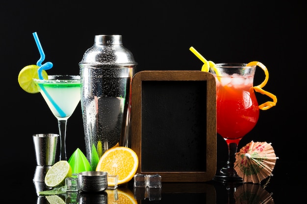 Vorderansicht verschiedener Cocktails mit Shaker und Tafel