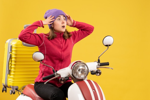 Vorderansicht verwirrte junge Frau auf Moped, die ihren Kopf hält