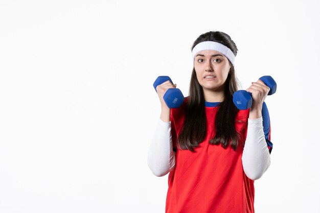 Vorderansicht verwirrte junge Frau in Sportkleidung mit blauen Hanteln