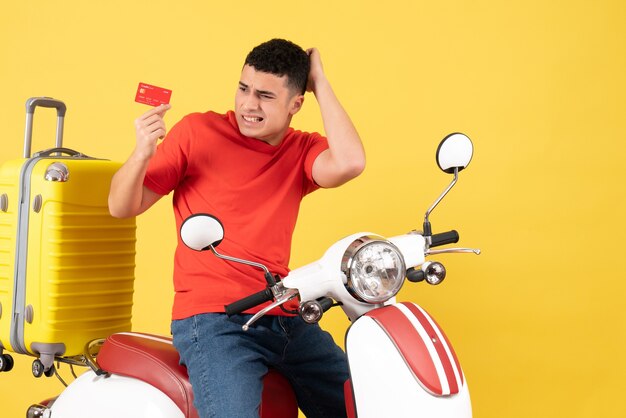 Vorderansicht verwirrte jungen Mann im roten T-Shirt auf Moped-Haltekarte