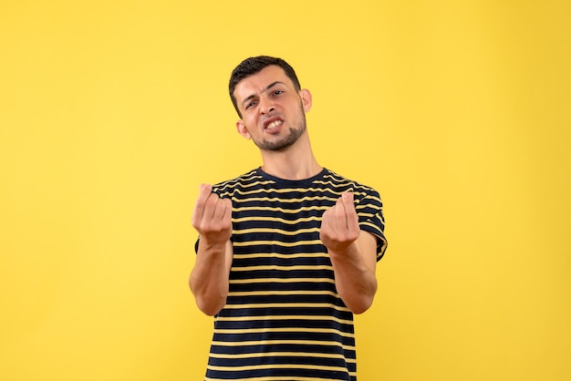 Vorderansicht verwirrte jungen Mann im schwarz-weiß gestreiften gelben isolierten Hintergrund des T-Shirts