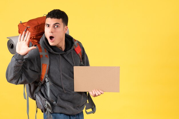 Kostenloses Foto vorderansicht verwirrte reisenden mann mit rucksack, der pappe winkende hand hält