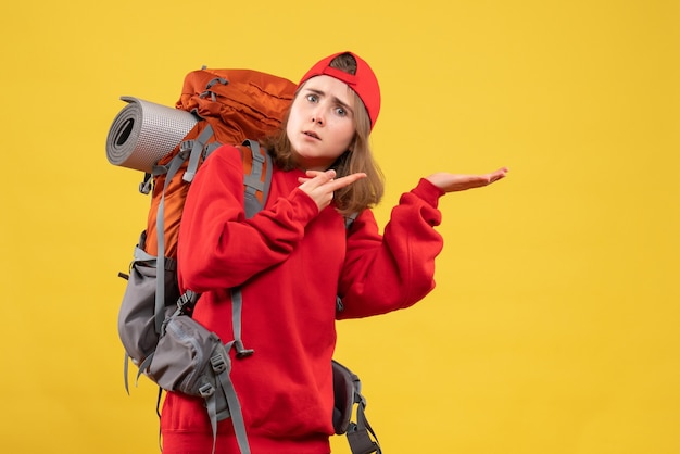 Vorderansicht verwirrte weibliche Reisende mit Rucksack, der etwas zeigt