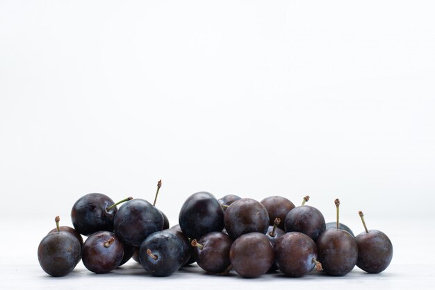 Vorderansicht von blauen Pflaumen rund auf der weißen Oberfläche gebildet