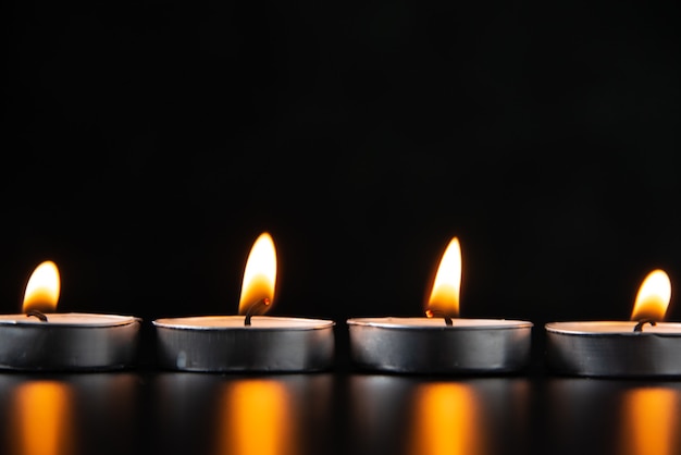 Vorderansicht von brennenden Kerzen auf dunkler Oberfläche
