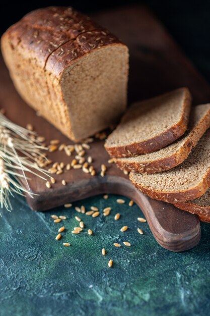 Vorderansicht von diätetischem Schwarzbrot Spikes Weizen auf Holzbrett auf blauem Hintergrund dunkler Farben